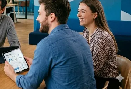 Beschäftigte schauen gemeinsam auf ein Tablet mit dem bKV-Mitarbeiterportal
